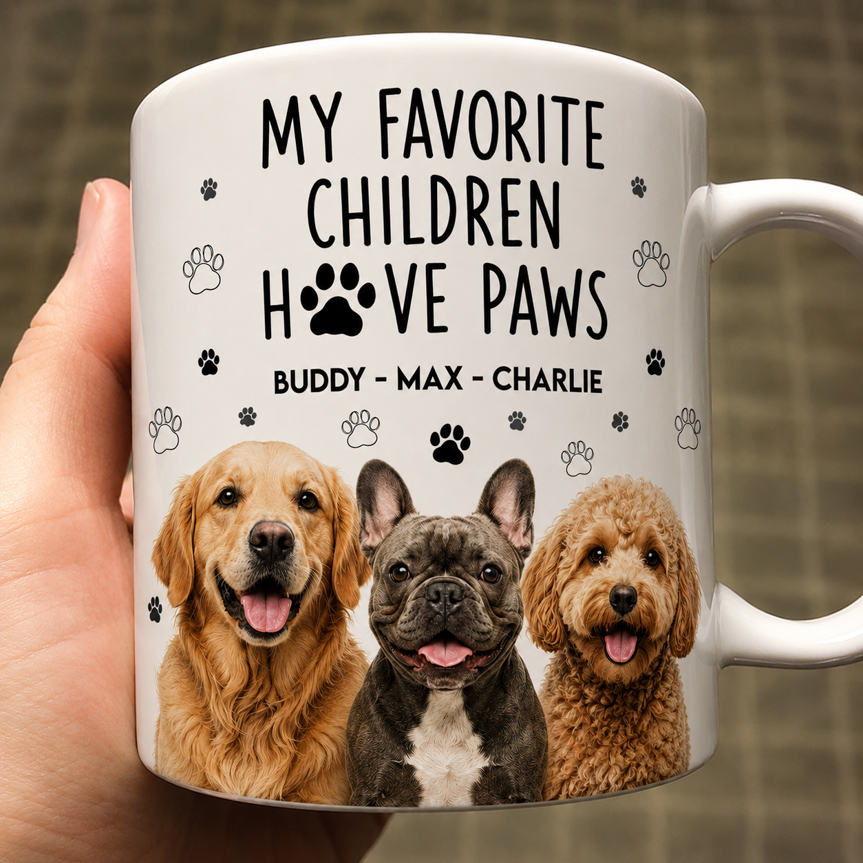 Mug with images of three dogs and text 'My favorite children have paws' held by a hand.
